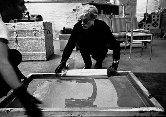 Illustration for: Andy Warhol working on a silkscreen print of “Campbell Soup I” at The Factory, New York, 1964. © Ugo Mulas Heirs. All rights reserved. / 2025 The Andy Warhol Foundation for the Visual Arts